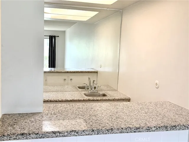 a bathroom with a granite countertop sink and a mirror