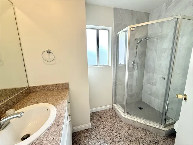a bathroom with a granite countertop sink a mirror and shower