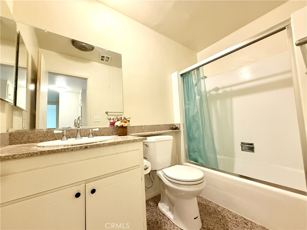 1301 South Atlantic Boulevard, Unit 234C Monterey Park, CA 91754 - Photo 22 of 27 a bathroom with a granite countertop sink toilet a mirror a vanity and shower