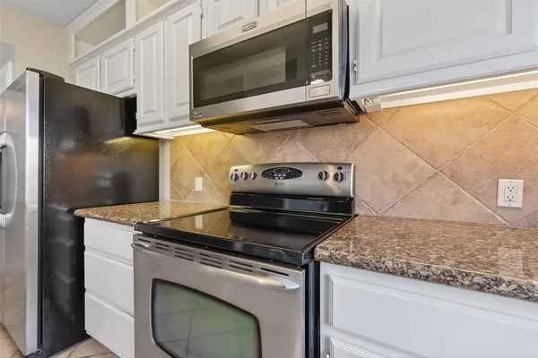 a kitchen with granite countertop white cabinets and stainless steel appliances