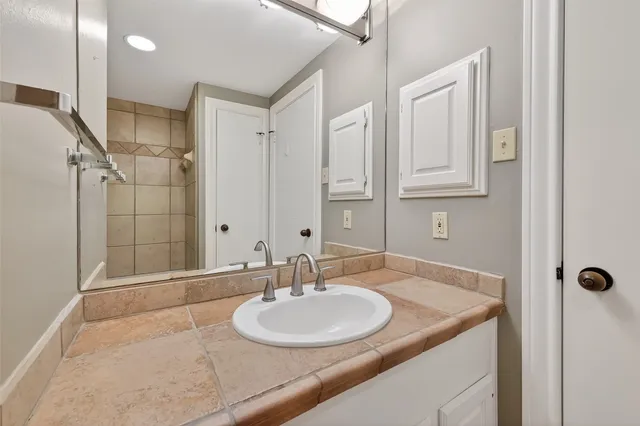 a bathroom with a granite countertop sink a mirror and shower