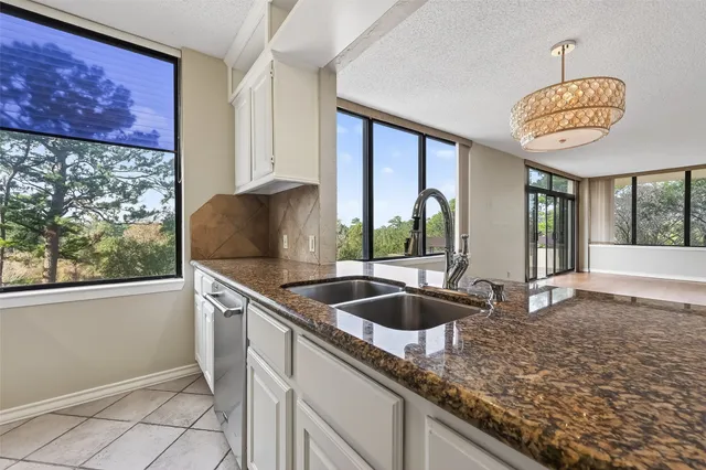a kitchen with stainless steel appliances granite countertop a sink a oven and a large window