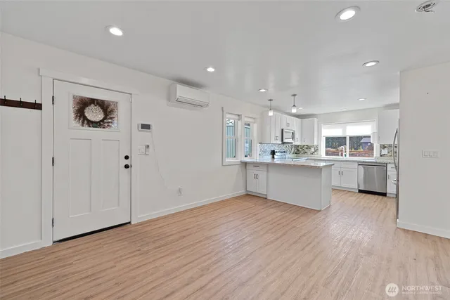 a kitchen with stainless steel appliances granite countertop a refrigerator a sink dishwasher a oven and white cabinets with wooden floor