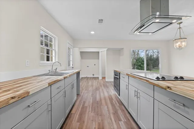 a view of an empty room with wooden floor and a kitchen