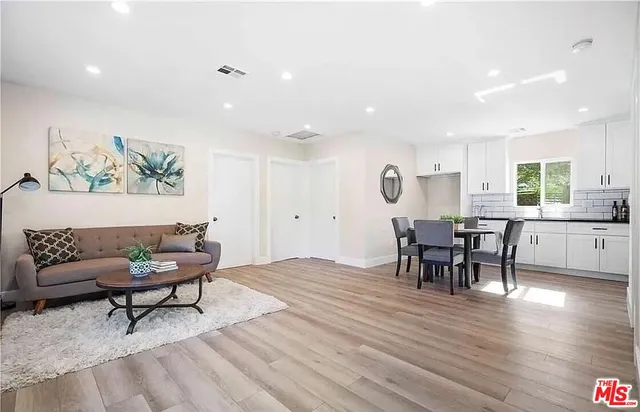 a living room with furniture and a dining table with wooden floor