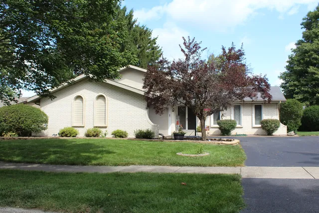 a front view of a house with a yard and trees