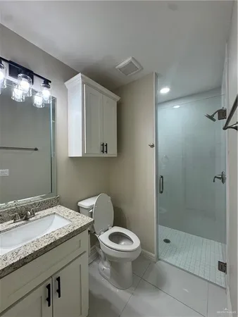a bathroom with a granite countertop sink a toilet and shower