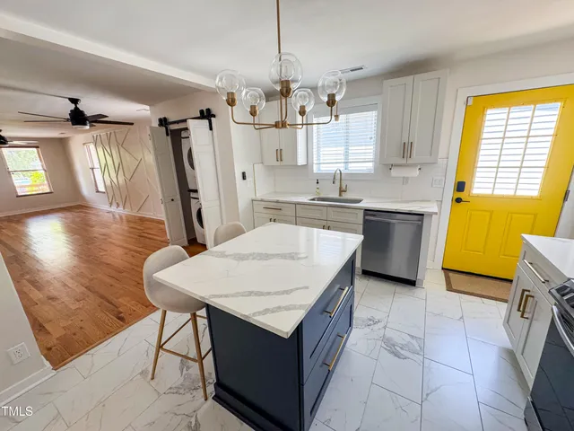 a kitchen with kitchen island granite countertop a sink a counter top space and stainless steel appliances