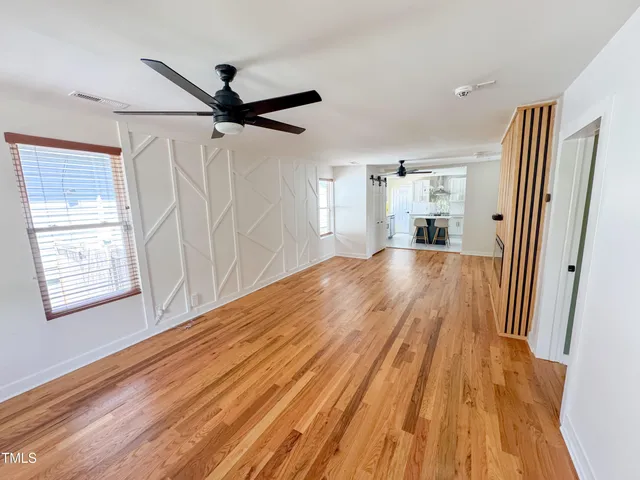 a view of a big room with wooden floor a ceiling fan and windows