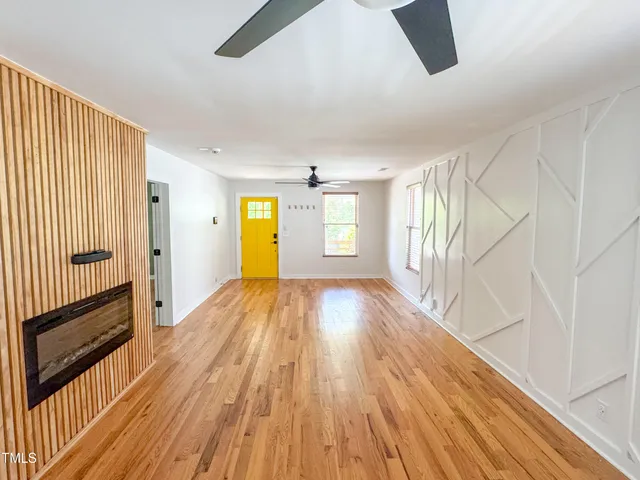 a view of empty room with wooden floor and fan