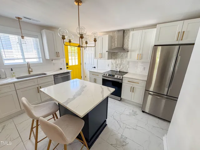 a kitchen with stainless steel appliances a refrigerator a sink a stove a table and chairs