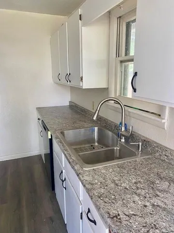a kitchen with granite countertop a sink a stove and cabinets