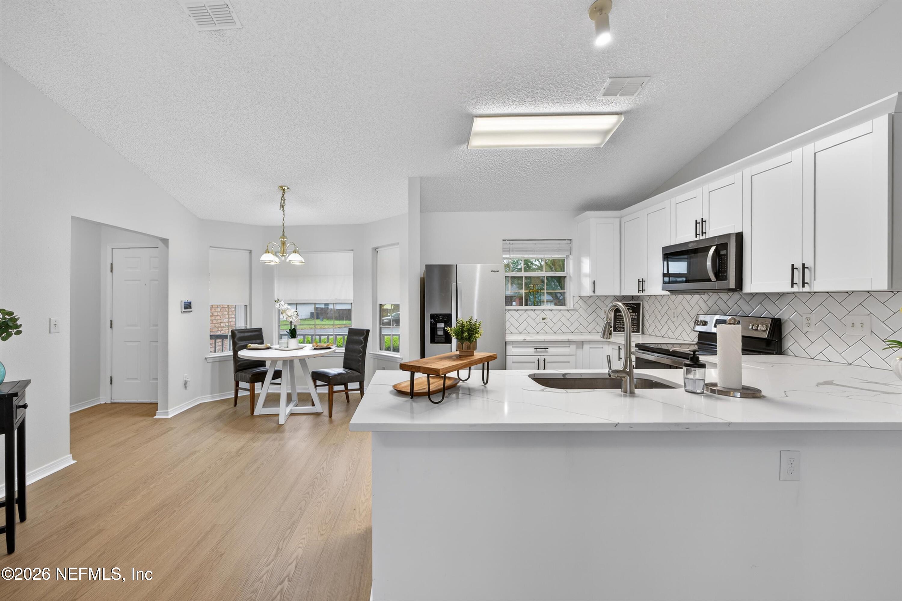 2411 Paris Mill Road Jacksonville, FL 32221 - Photo 13 of 36 a kitchen with stainless steel appliances dining table chairs and cabinets