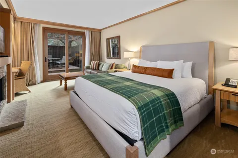 a spacious bedroom with a bed a mirror and a large window