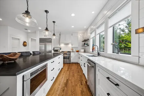 a large kitchen with stainless steel appliances granite countertop a lot of counter space and wooden floors