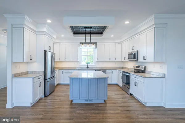 a kitchen with kitchen island granite countertop a sink refrigerator and cabinets