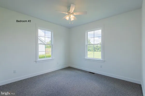 an empty room with windows and a ceiling fan