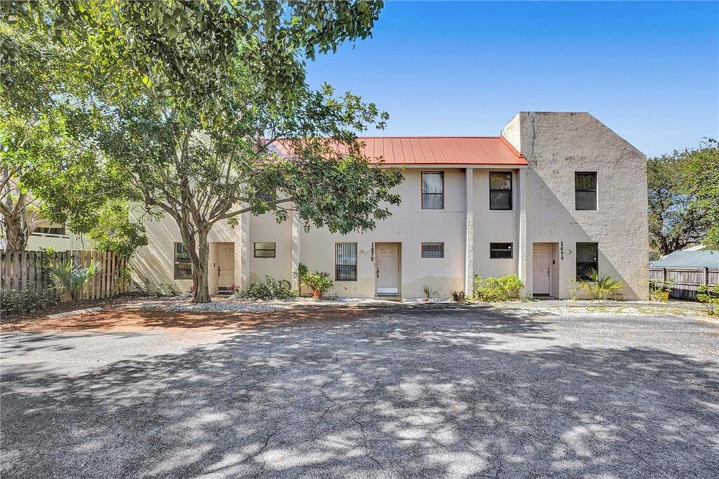1679 Northwest 15th Vista Boca Raton, FL 33432 - Photo 3 of 15 a front view of a house with a dirt yard and a large tree