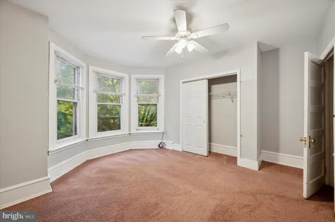 an empty room with windows and fan