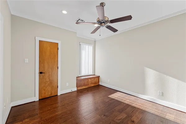 an empty room with wooden floor closet and windows