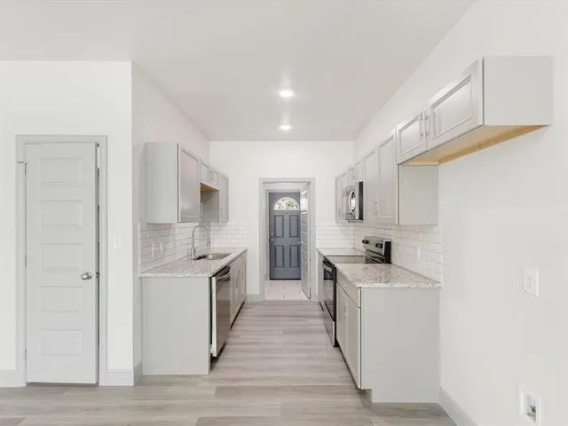 a kitchen with stainless steel appliances a sink a stove a refrigerator cabinets and a window