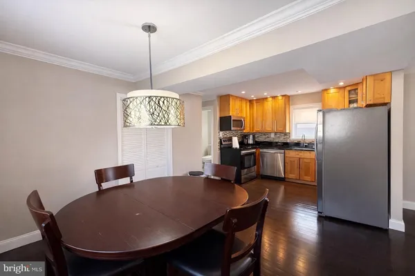 a kitchen with stainless steel appliances granite countertop a dining table chairs refrigerator and window