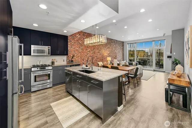 a kitchen with stainless steel appliances granite countertop a stove top oven a sink dishwasher a dining table and chairs with wooden floor