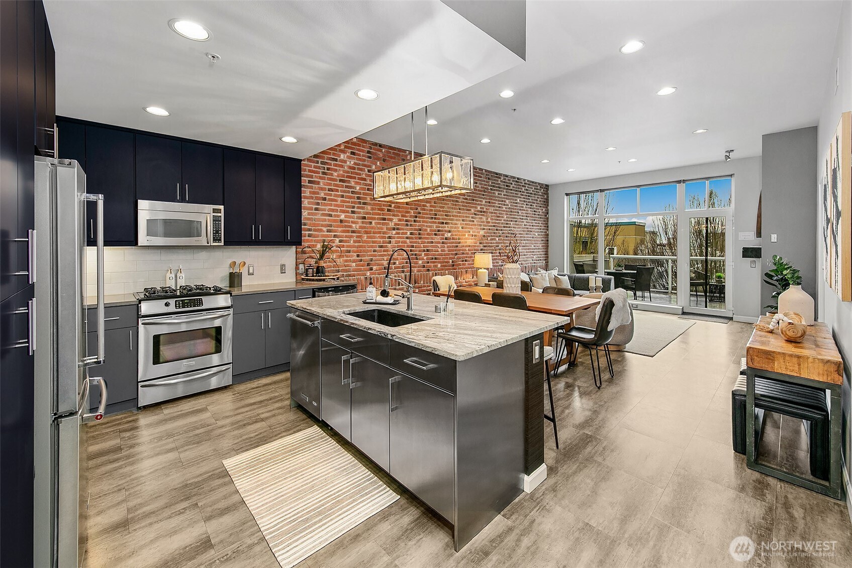 17 West Mercer Street, Unit 302 Seattle, WA 98119 - Photo 3 of 28 a kitchen with stainless steel appliances granite countertop a stove top oven a sink dishwasher a dining table and chairs with wooden floor
