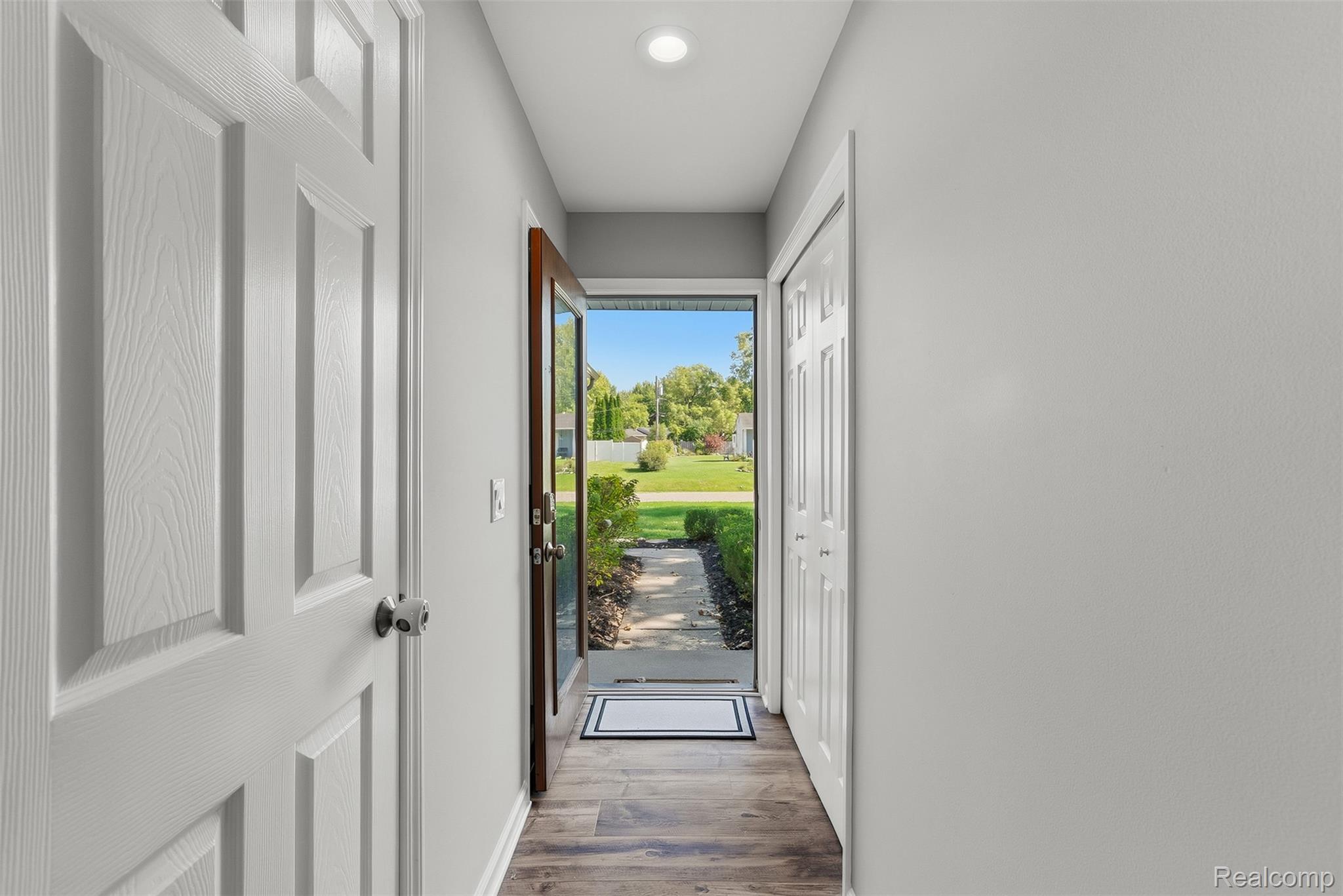 Entryway featuring wood-finish flooring, recessed lighting, and a paneled white door