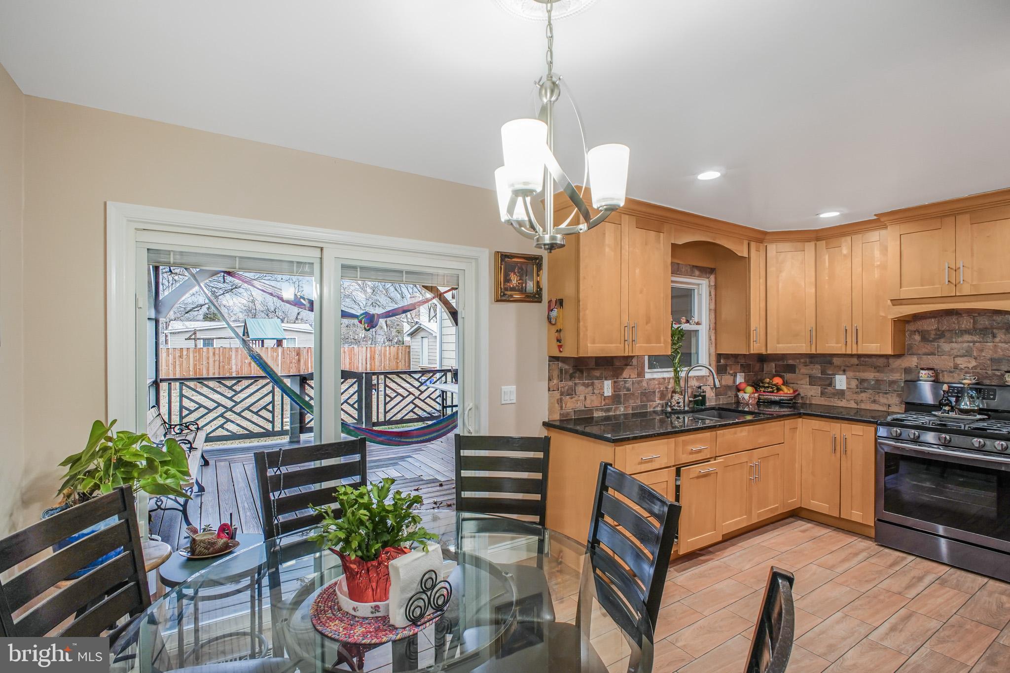 8227 Frye Road Alexandria, VA 22309 - Photo 5 of 45 a kitchen with stainless steel appliances granite countertop a stove a sink a microwave a dining table and chairs with wooden floor