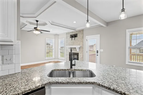 a kitchen with granite countertop a sink a counter top space and cabinets