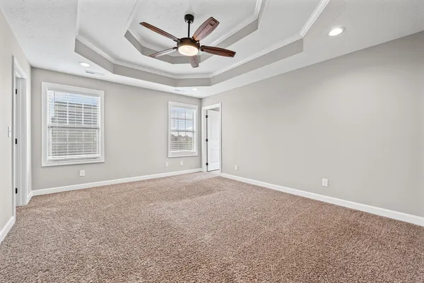 an empty room with windows and ceiling fan