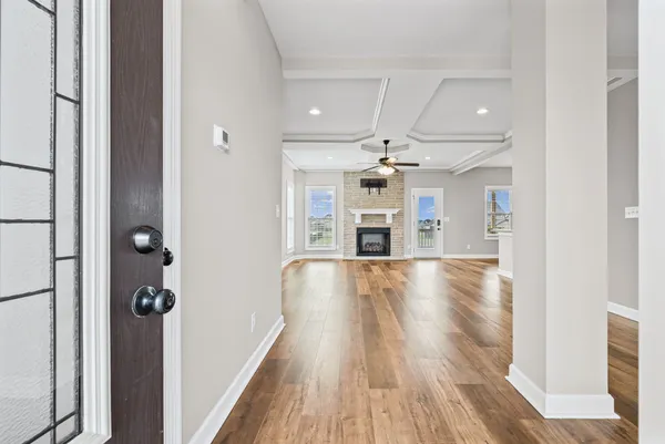 a view of a hallway with wooden floor and a kitchen