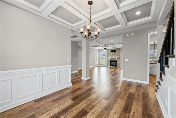 a view of a hallway with wooden floor and a kitchen