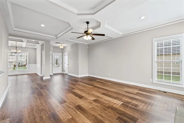 a view of an empty room with window and wooden floor