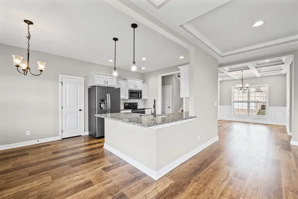 a view of a kitchen with stainless steel appliances a center island wooden floor and a chandelier
