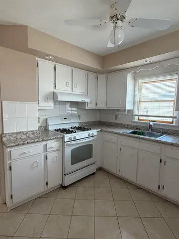 a kitchen with granite countertop white cabinets white appliances with a sink and dishwasher
