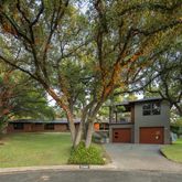 a front view of a house with a garden and trees