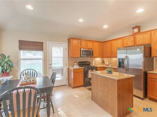 a kitchen with refrigerator a stove a sink dishwasher and wooden cabinets with wooden floor