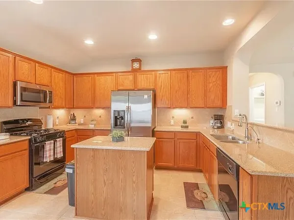 a kitchen with stainless steel appliances granite countertop a sink stove refrigerator and cabinets