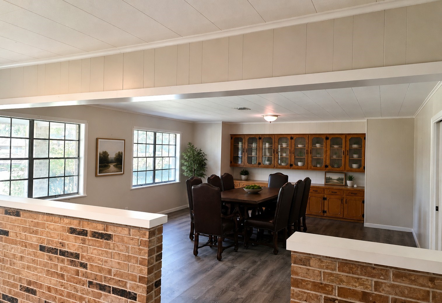 201 Verna Street Jasper, TX 75951 - Photo 5 of 24 This spacious living area with large windows offering ample natural light. It features a partial brick partition and vinyl flooring, leading to a built-in wooden cabinet unit, perfect for storage or display.
