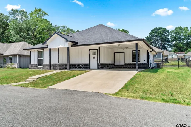a view of a house with a yard and large tree