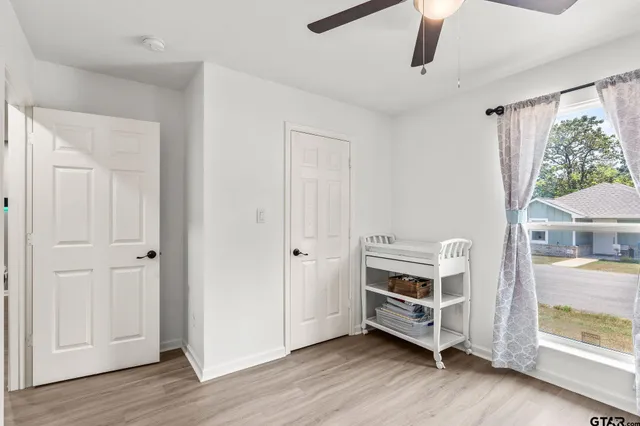 a view of an empty room with a window and wooden floor