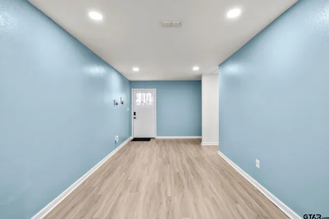 an empty room with wooden floor and windows