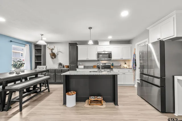 a kitchen with stainless steel appliances a stove a sink dishwasher a refrigerator white cabinets and wooden floor