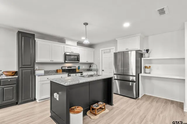 a kitchen with stainless steel appliances granite countertop a refrigerator a stove a sink dishwasher and a refrigerator with wooden floor