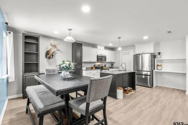a kitchen with a dining table chairs refrigerator and microwave