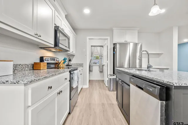 a kitchen with stainless steel appliances granite countertop a lot of counter space and wooden floors