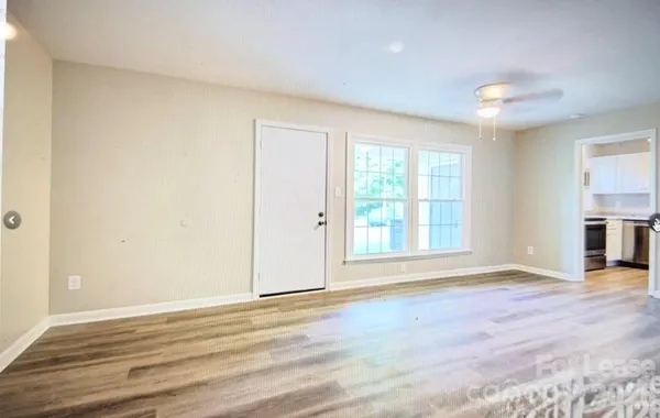 a view of an empty room with wooden floor and a window