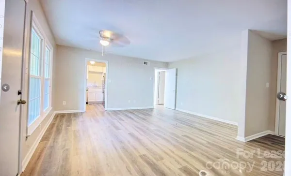 a view of empty room with wooden floor and fan